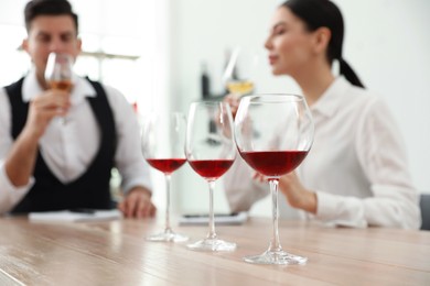 Sommeliers tasting different sorts of wine at table indoors