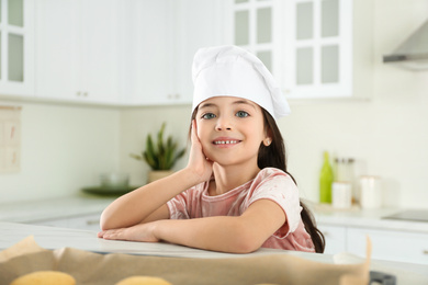 Cute little girl wearing chef hat in kitchen