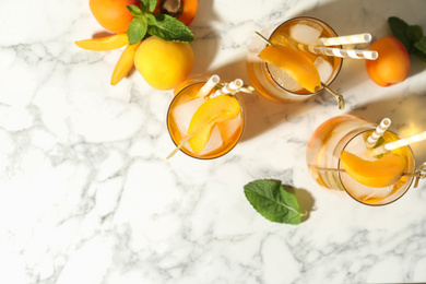 Photo of Delicious refreshing drink with apricot on white marble table, flat lay. Space for text