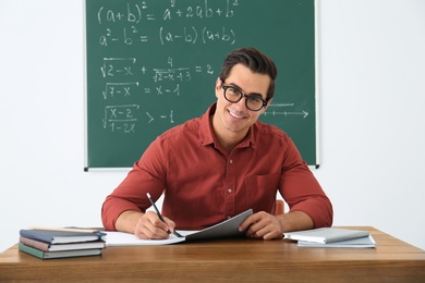 Young teacher working at table in classroom