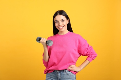 Woman with dumbbell as symbol of girl power on yellow background. 8 March concept