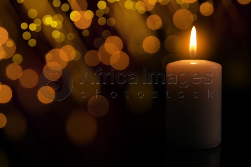 Image of Wax candle burning in darkness, bokeh effect. Christmas Eve
