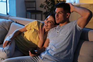 Couple watching movie on sofa at night