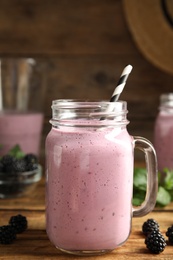 Tasty fresh milk shake with blackberries on wooden table