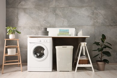 Photo of Stylish laundry room with modern washing machine. Interior design