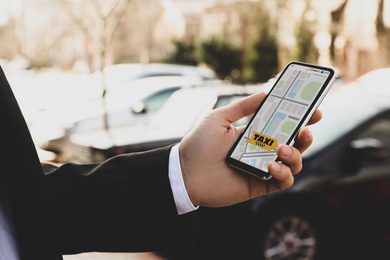 Businessman ordering taxi with smartphone on city street, closeup