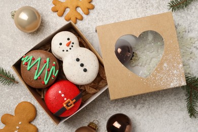 Photo of Tasty Christmas macarons in box and festive decor on table, flat lay