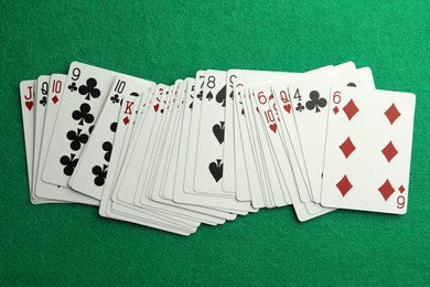 Deck of playing cards on green table, top view. Poker game