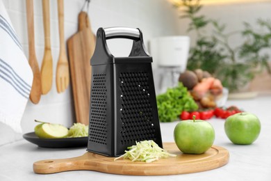 Grater and fresh ripe apples on kitchen counter