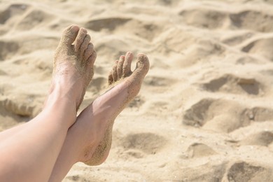 Photo of Woman resting on sandy beach, closeup of feet. Space for text