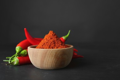 Paprika powder and fresh chili peppers on black table. Space for text