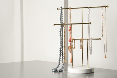 Holder with set of luxurious jewelry on grey table. Space for text