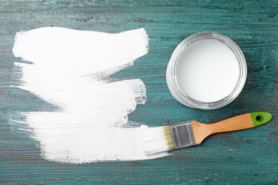 Can of white paint and brush on teal wooden background, flat lay. Space for text