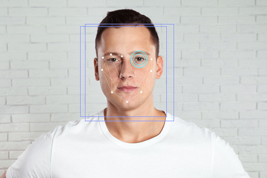 Facial recognition system. Man with scanner frame and digital biometric grid against brick wall