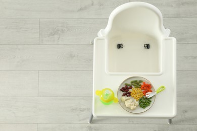 Baby high chair with healthy food and water, top view. Space for text