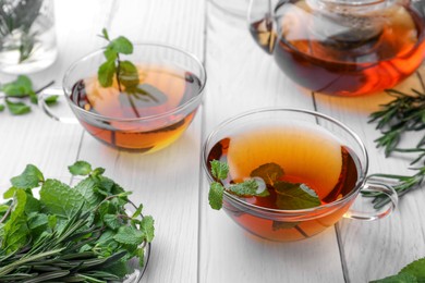 Aromatic herbal tea with mint and rosemary on white wooden table