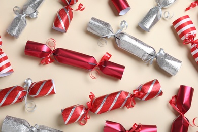 Red and silver Christmas crackers on beige background, flat lay
