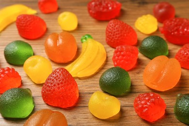 Delicious gummy fruit shaped candies on wooden table, closeup