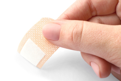 Woman putting sticking plaster on white background, closeup. First aid item