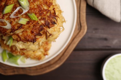 Photo of Tasty parsnip cutlets with green onion on wooden table, top view