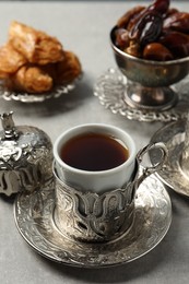 Photo of Tea, baklava dessert and date fruits served in vintage tea set on grey table, closeup. Space for text
