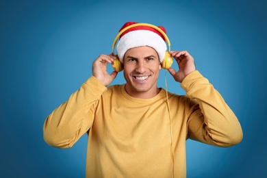 Happy man with headphones on blue background. Christmas music