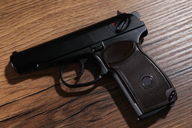 Handgun on wooden table, top view. Semi-automatic pistol