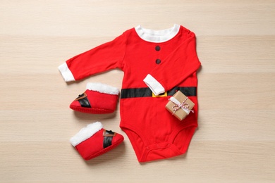 Christmas outfit for little baby on wooden background, flat lay