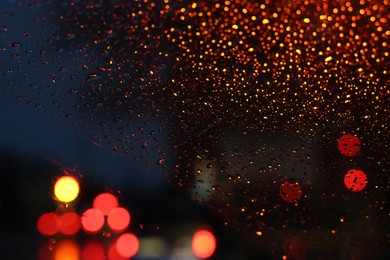 Blurred view of road through wet car window at night. Bokeh effect