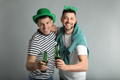 Happy men in St Patrick's Day outfits with beer on light grey background