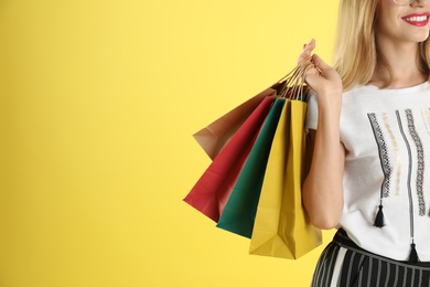 Young woman with shopping bags on color background, closeup. Space for text