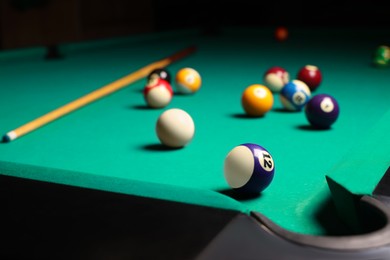 Photo of Many colorful billiard balls and cue on green table, space for text