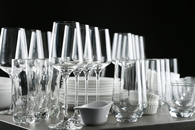 Set of empty glasses and dishware on table against black background