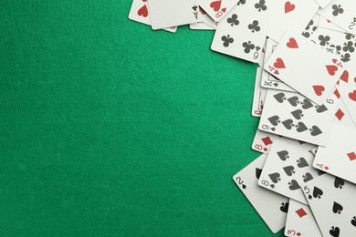 Scattered playing cards on green table, top view. Space for text