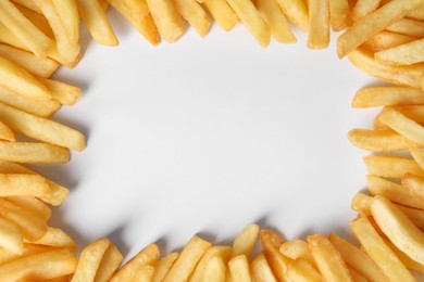 Frame of delicious french fries on white background, flat lay. Space for text