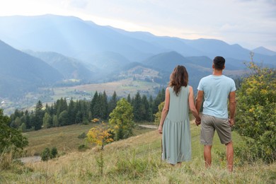 Couple enjoying beautiful mountain landscape, back view. Space for text
