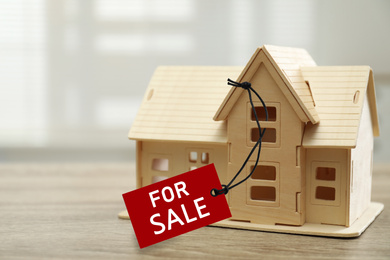 Wooden house model with SALE label on table