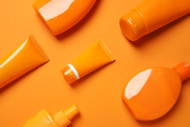 Flat lay composition with sun protection cosmetic products on orange background
