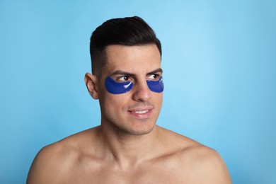 Man with under eye patches on light blue background