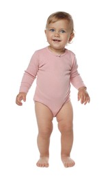 Cute baby girl in pink bodysuit learning to walk on white background