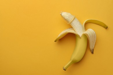 Banana with condom on orange background, top view and space for text. Safe sex concept