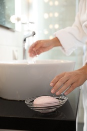 Young woman taking soap bar to wash hands in bathroom, closeup