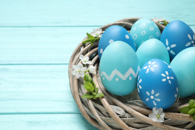 Nest with Easter eggs on light blue wooden background, closeup