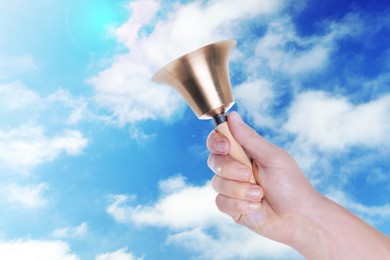 Woman with school bell against blue sky, closeup