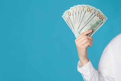 Woman holding dollar banknotes on turquoise background, closeup with space for text. Money exchange concept