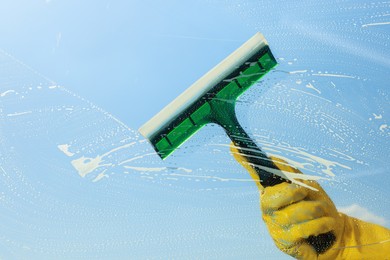 Person cleaning glass with squeegee , view from inside