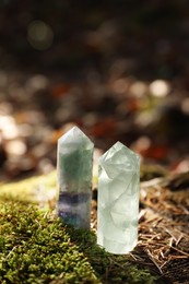 Photo of Beautiful quartz crystals on green moss in forest. Space for text
