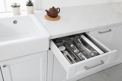 Photo of Open drawer with different utensils in kitchen