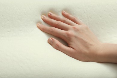 Photo of Woman touching orthopedic memory foam pillow, closeup