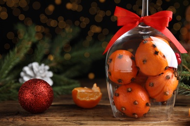 Christmas composition with tangerine pomander balls in wineglass on wooden table. Space for text